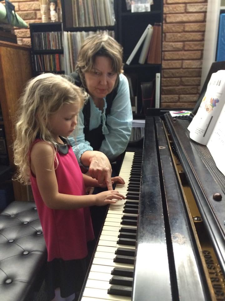 Debra Peters teaching piano to a young girl student at the grand piano