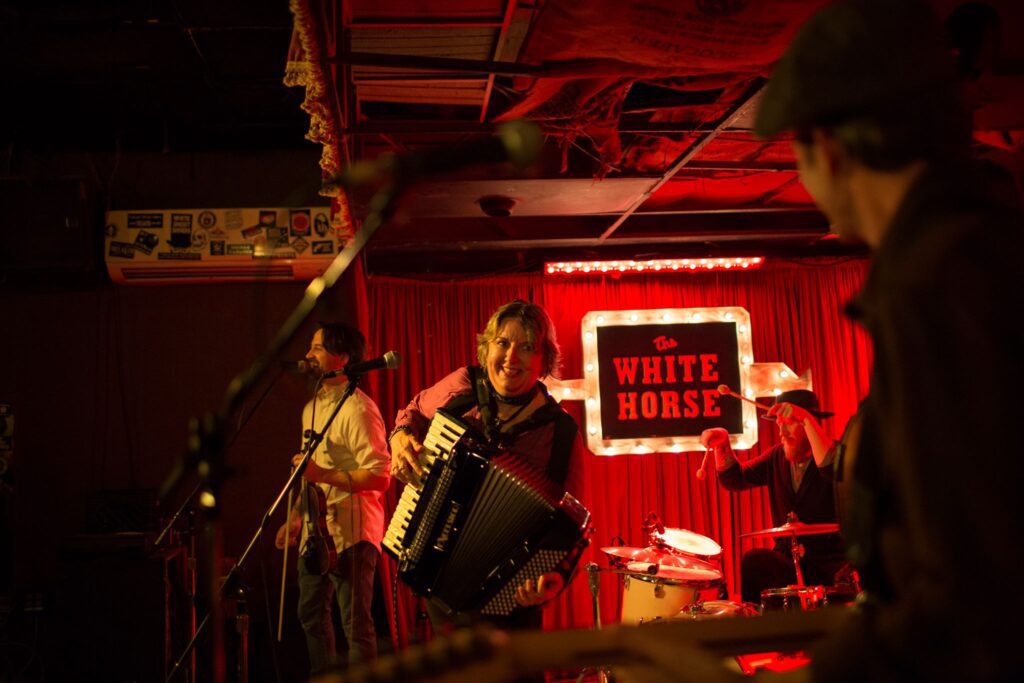 Debra Peters playing accordion on stage at The White Horse in Austin with Chansons et Soulards Band