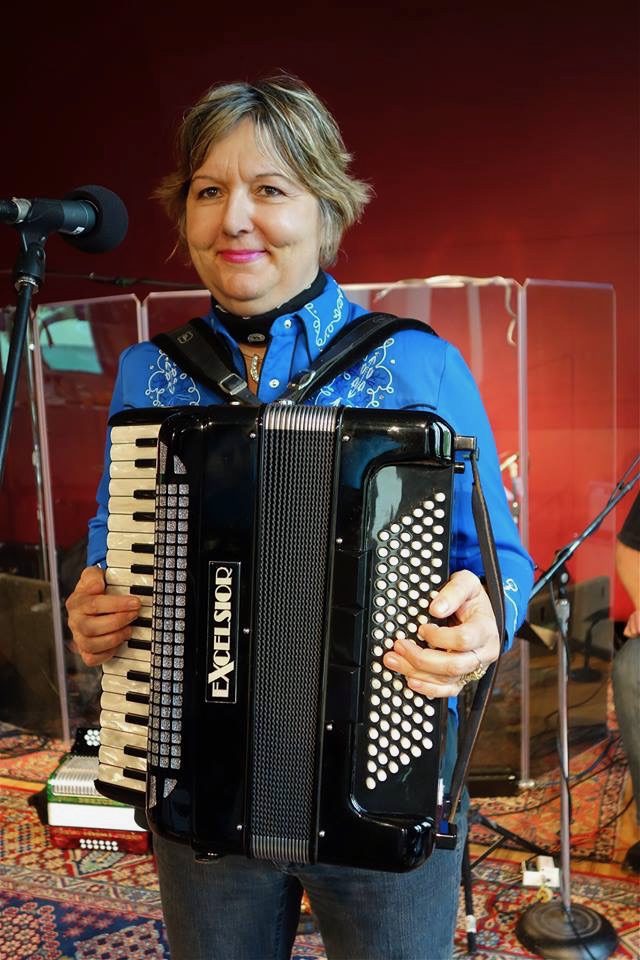 Debra Peters smiling while holding her black Excelsior piano accordion at KUT Radio, Austin, Texas – 2013