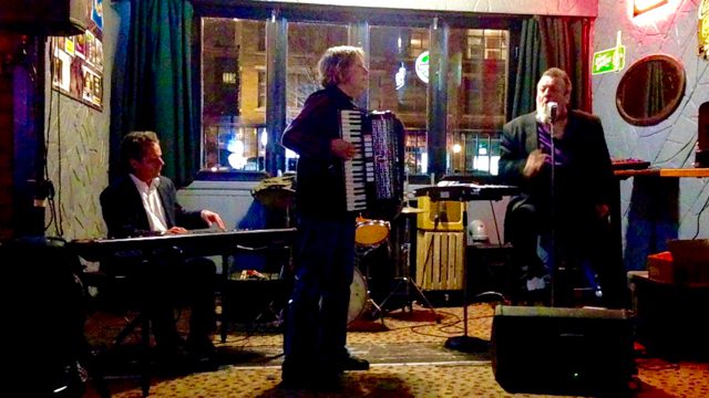 Debra Peters playing accordion with Harpdog Brown on harmonica, Steve Taylor on drums, and Dave Webb on piano at the Ivanhoe Pub in Vancouver