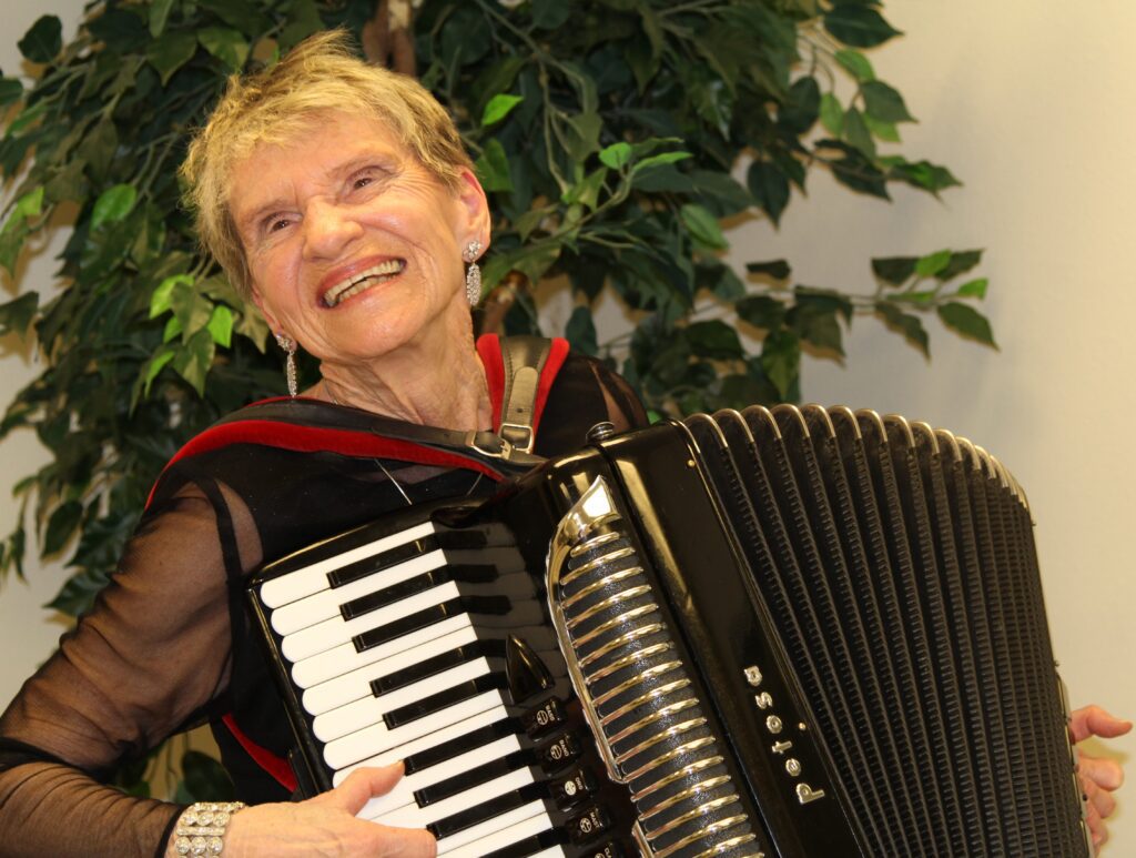 Lou LeBrun playing accordion with a big smile