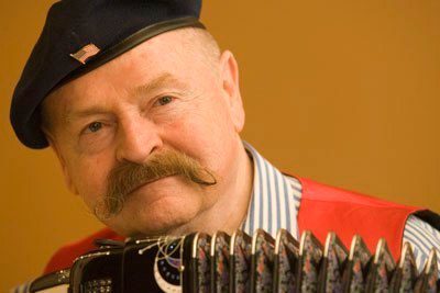 Portrait of accordionist Nick Ballarini wearing a beret and red vest